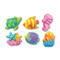 Six vibrant underwater fridge magnets from the 4M Mould & Paint Kit - Sealife by 4M are showcased. The collection features designs such as a green turtle, a yellow fish with red stripes, a pink seahorse, two starfish on pink coral, a green and purple fish, and an orange coral reef with small yellow fish. Additionally, some of these delightful magnets glow in the dark!