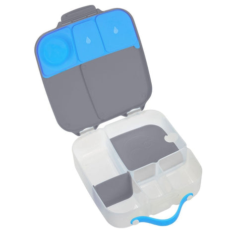 The B.Box Lunch Box by B.Box is a flexible lunchbox with a blue handle, featuring multiple compartments in the bottom portion, some of which are removable. The top lid has sections for an ice pack and additional smaller compartments. With leak-proof silicone seals, this lunchbox keeps your food fresh in its predominantly white, black, and blue design.