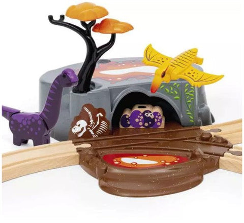 Introducing the Brio World Dinosaur Adventure Set by Brio: a toy dinosaur playset featuring a purple dinosaur, a yellow pterosaur, an orange-leaved tree, and a rock with a cave painted with dinosaur bones. Wooden railway tracks are connected, passing over a lava pit towards the cave entrance for endless fun.