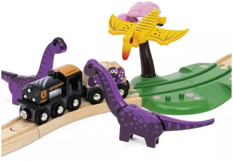 The Brio World Dinosaur Adventure Set by Brio is a whimsical play set featuring a black engine and two dinosaurs on wooden tracks, surrounded by toy dinosaurs. Two purple ones and a yellow pterodactyl perched on a green stand complete this colorful train set with dinosaurs.