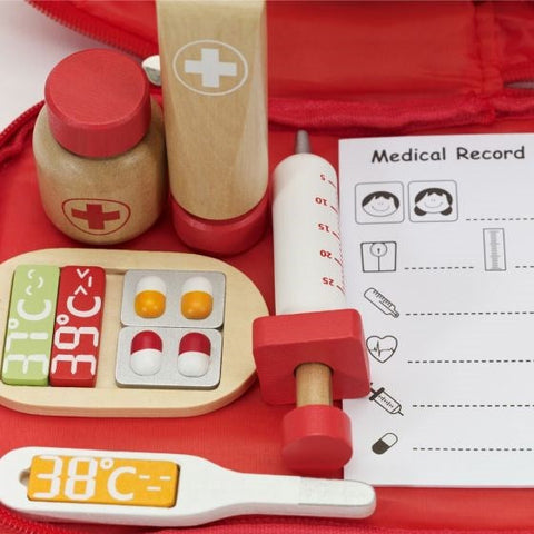 The Classic World Doctor Case by Classic World comes with a variety of items perfect for imaginative roleplay, including a thermometer displaying 38°C, assorted wooden medicine bottles, a toy syringe, and a wooden tray filled with colorful pills and tablets. Additionally, the red bag contains a paper medical record sheet to enhance the play experience.