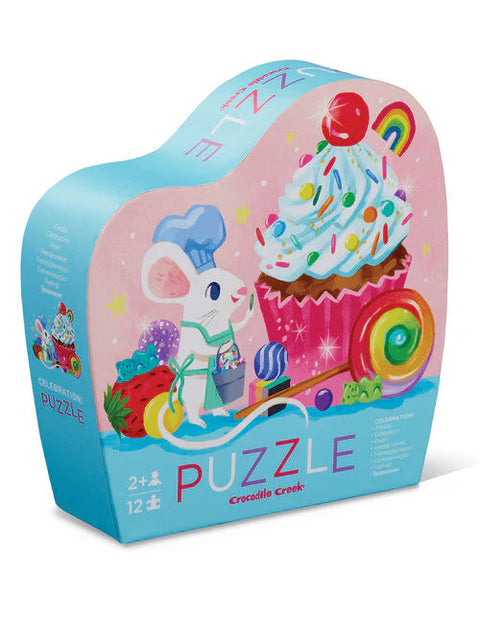 The Crocodile Creek 12pc Mini Puzzle - Celebration by Crocodile Creek is a vibrant toddler puzzle box that showcases a charming illustration of a white mouse wearing a chef's hat and apron while holding a lollipop. The background features an eye-catching cupcake with sprinkles, surrounded by candy and stars. Ideal for children aged 2 and up, this 12-piece puzzle helps develop fine motor skills and hand-eye coordination.