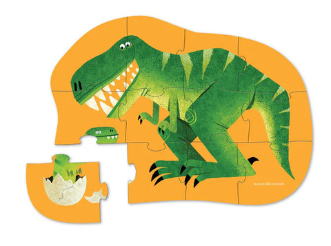 A partially completed Crocodile Creek 12pc Mini Puzzle - Just Hatched, from the Crocodile Creek brand, depicting a green dinosaur with sharp teeth on a bright yellow background. One puzzle piece, showing a small portion of the dinosaur, is placed outside the main jigsaw puzzle, perfect for enhancing hand-eye coordination.