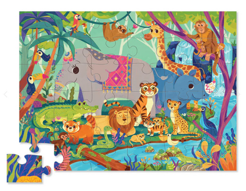 The Crocodile Creek 36pc Floor Puzzle - In the Jungle from Crocodile Creek features a vibrant jungle scene with a variety of animals such as a peacock, toucans, an alligator, lions, elephants, a giraffe, tigers, monkeys, and a panda. Two puzzle pieces are detached and placed on the left side.