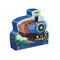 A uniquely shaped, train-themed box labeled "Crocodile Creek 36pc Foil Floor Puzzle - Puzzle All Aboard" by Crocodile Creek, featuring a vibrant blue and red train with a star on its front. The colorful storage box also indicates that it contains a 36-piece floor jigsaw puzzle with colorful illustrations.