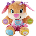 The Fisher-Price Laugh & Learn Smart Stages Sis is an adorable plush toy dog with pink floppy ears and two purple bows. It has a pink nose, blue eyes, and wears a pink skirt and a shirt adorned with colorful letters. This baby learning toy includes interactive buttons on its paws labeled "Hand," "Foot," and "Music," which activate various playful functions.