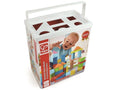 A HAPE white container, complete with a handle, holds the HAPE 101pcs Blocks set. This set features colorful wooden blocks that are ideal as a first block set, perfect for children aged 12 months and older. The label displays an image of a smiling child playing with these sturdy beech blocks. Designed to develop dexterity, the set includes 101 pieces.