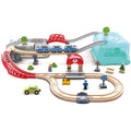 The HAPE City Train Bucket Set by HAPE features a wooden train set with multiple tracks, a red bridge, a train station, and a toy train. Ideal for imaginative play, the set includes small figurines of people, cars, trees, and traffic signs. The tracks are creatively laid out with elevated sections and can be stored in a city-themed storage box.