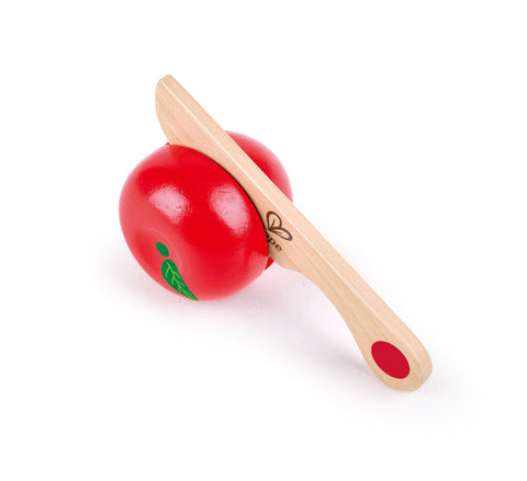 The HAPE Farm Shop Fruit Playset by HAPE depicts a food item being sliced. It features a red apple with a green leaf, split down the middle, and includes a safe play knife placed between the halves to simulate cutting and enhance fine motor skills.