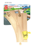 The image shows a pack of Hape Adjustable Switch Track 2pc for toy train sets. This children's toy from the brand HAPE includes two wooden switch tracks with a yellow and black adjustable mechanism. The packaging features a background image of a high-speed train and is labeled for ages 3 and up.