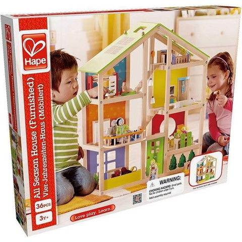 Two children play with a furnished dollhouse inside a room. The packaging indicates it is a HAPE All Season Doll House Furnished, suitable for ages 3 and up, and includes 36 pieces. The house features moveable stairs and four room sets. The slogan reads "Love play. Learn." A warning label is visible on the box.