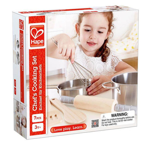 The packaging for the "Hape Chef's Cooking Set" showcases a young child using a whisk to prepare a healthy meal, surrounded by cooking pots and utensils. This 7-piece set is designed for children aged 3 and up. The box features a primarily white and red color scheme with prominent product and safety information.