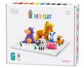 Box of "Hey Clay 15 pack - Animals" air-dry modeling clay set for making animal figurines. The box showcases various colorful clay animals, including a cow, horse, sheep, pig, and other figures. The set includes 15 cans of Hey Clay and 3 sculpting tools for play-based learning, suitable for ages 3 and above.