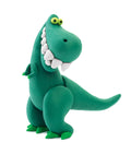 A green, cartoonish clay dinosaur stands upright against a white background. Crafted from the Hey Clay 15 pack - Dinos Play-Set by Hey Clay, this dinosaur features large teeth, green eyes with yellow pupils, small arms, and large feet. Its playful expression gives it a friendly appearance while promoting sensory development in kids.