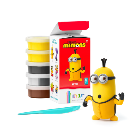 A Hey Clay Single Pack Minions - Kevin activity set, which includes tubs of soft modeling clay and a plastic sculpting tool, sits beside an open box, showcasing a completed yellow Minion wearing goggles and blue overalls. This fun project by Hey Clay is perfect for enhancing fine motor skills.