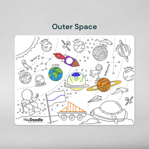 The Hey Doodle Silicone Playmat - Outer Space (Large) features various space-themed illustrations, including astronauts, planets, a rocket, a spaceship, and space equipment. This reusable silicone mat offers open-ended drawing prompts with some elements already colored and others left for coloring. The label "Hey Doodle" is at the bottom.