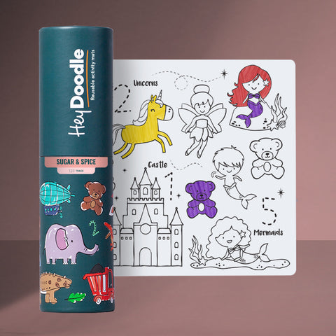 A cylindrical container labeled "Hey Doodle" stands next to a Hey Doodle Silicone Playmat - Sugar & Spice (Mini), featuring outlines of various characters, including fairies and unicorns, a castle, teddy bears, and mermaids. The container has a dark green label and the mat showcases playful illustrations perfect for coloring with markers.