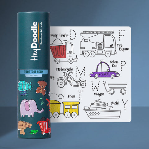 A cylindrical container labeled "Hey Doodle Silicone Playmat - Toot Toot Honk (Mini)" stands beside a reusable silicone mat. The mat features outlined drawings of various vehicles, such as a dump truck, fire engine, motorcycle, and police car, each labeled with their names. Use washable markers for endless fun!