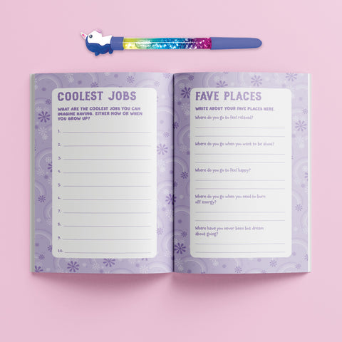 Description: The Hinkler Journal Kit - Super Sweet features an open journal with pages labeled "Coolest Jobs" and "Fave Places" set against a pink background. Included is a colorful unicorn pen, placed horizontally above the journal, which boasts a vibrant purple and white patterned design. This set by Hinkler is perfect for jotting down creative prompts.