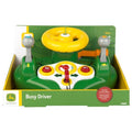 The John Deere Busy Driver playset features a bright yellow steering wheel, green and red shifters, and a panel with various buttons. Packaged in a John Deere-themed green and yellow box, this set includes realistic sounds suitable for children aged 12 months and up.