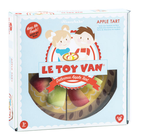 The box labeled "LE TOY VAN" contains the Le Toy Van Apple Tart Wooden Playset for children aged 3 and up. Crafted from sustainable rubberwood and painted with safe, non-toxic paints, the box features an illustration of two children holding an apple tart and highlights "Delicious Apple Tart" with a red banner.