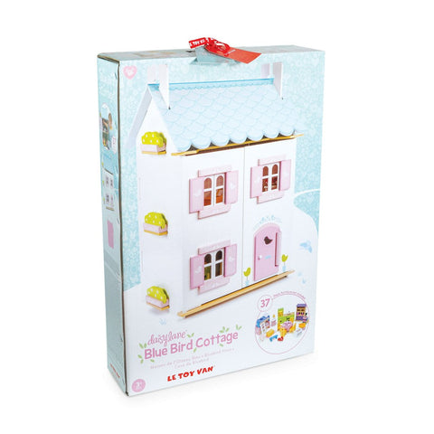 A boxed Le Toy Van Blue Bird Cottage with Furniture by LE TOY VAN, featuring a charming wooden doll's house with pink window shutters and door. The detailed package highlights the 37-piece furniture set included and boasts intricate illustrations, complete with a red ribbon handle on top.