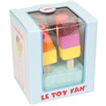 A boxed set of vibrant wooden ice lollies from LE TOY VAN. The toys are enclosed in a blue package with a clear front, displaying three colorful lollies adorned with various patterns. The brand name "LE TOY VAN" is printed in red on the box.