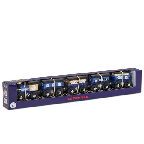 Set of five wooden toy train carriages in blue, beige, and black variations, each with windows and detailing, made from sustainable rubberwood. Packaged in a long, rectangular purple box reading "LE TOY VAN" in red letters near the bottom center. Perfect for a Le Toy Van Twilight Train adventure!