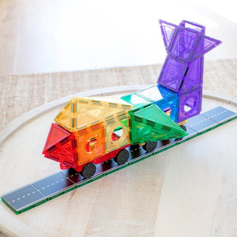 A colorful vehicle made of Learn & Grow Rainbow Magnetic Tiles Car Base Pack 2pc by Learn & Grow sits on a miniature road track. The vehicle's body features tiles in red, orange, yellow, green, blue, and purple, with a geometric structure at the front and a tall, angular shape at the back. Perfect for fostering STEM skills in vehicle construction.