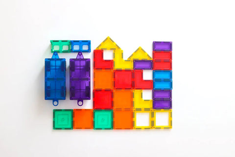 A vibrant display of magnetic tiles creating a playful pattern. The tiles, from the Learn & Grow Rainbow Magnetic Tiles Car Expansion Pack 28pc by Learn & Grow, come in various shapes like squares, rectangles, and triangles in bright colors such as blue, green, red, orange, yellow, and purple are arranged on a white background.