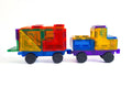 The Learn & Grow Rainbow Magnetic Tiles Car Expansion Pack 28pc features colorful magnetic building blocks assembled into the shape of a two-car train. The blocks, from Learn & Grow, come in vibrant hues of red, yellow, green, blue, and purple with black rubber wheels on both cars. They are displayed against a plain white background.