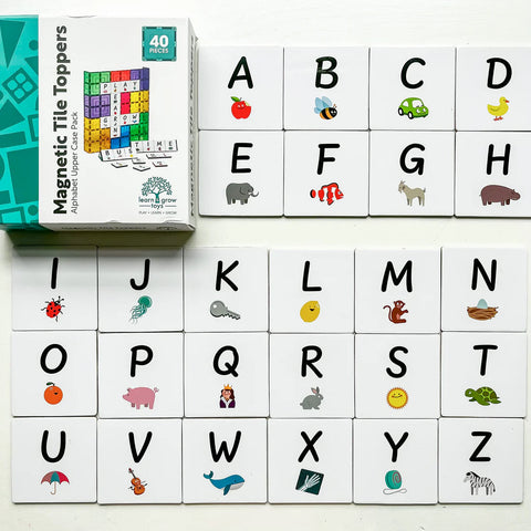 A set of 40 magnetic tile toppers with uppercase letters and illustrations from the Learn & Grow Rainbow Magnetic Tiles Toppers - Alphabet Upper Case Pack are arranged neatly. Letters A to Z appear on individual white tiles, each accompanied by a corresponding animal or object, making them ideal for early literacy instruction. The box for the Alphabet Upper Case set from Learn & Grow is visible in the top left corner.