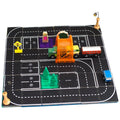 Introducing the Learn & Grow Rainbow Magnetic Tiles Toppers - Road Pack 40pc by Learn & Grow. This toy road playset on a black board features various street designs, including a green truck under an orange overpass, a red and yellow bus, and a blue car. It comes with road signs, pine tree models, several parking spaces, and a pedestrian figure near the overpass to enhance imaginative play for kids.