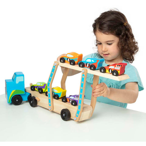 A young child, wearing a light blue shirt, is deeply engaged in arranging the six colorful race cars on the Melissa & Doug Mega Race-Car Carrier. This wooden truck by Melissa & Doug is designed with two levels and holds cars in various colors such as orange, yellow, purple, red, and green. The child's concentration on this activity helps to hone their motor skills. The truck itself features a striking blue color that enhances the visual appeal of playtime.
