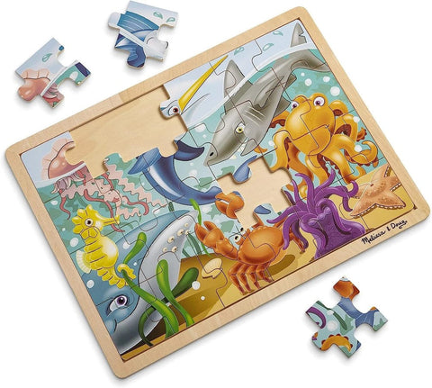 The Melissa & Doug Wooden Jigsaw Puzzle - Under The Sea 24pc by Melissa & Doug is partially assembled within its wooden frame, showcasing vibrant marine animals such as a shark, octopus, crab, seahorse, and jellyfish. Several puzzle pieces are scattered around the frame.