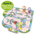 The image showcases the Orchard Toys Unicorn Fun Game by Orchard Toys. The board features winding paths adorned with smiling and frowning cloud illustrations, rainbows, and playful graphics. Perfect for a unicorn-themed party, it includes four game pieces shaped like cartoon clouds with different facial expressions.