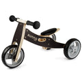 The Runna Mini - Black by RUNNA is a toddler bike designed with a wooden frame and three gray plastic wheels, perfect for beginners. This balance bike features a black seat, handlebars with black grips, and has "Runna Mini" printed on the frame, making it an ideal entry point into the world of balance bikes.