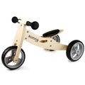 The Runna Mini - Natural, a small wooden balance bike with three wheels, is perfect for toddlers. It features black handles on the handlebars, a black seat, and silver and black plastic wheels. The words "RUNNA" and "mini" are printed on the frame. This toddler trike from RUNNA is an ideal introduction to children's bikes.