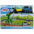 The Thomas & Friends Motorized Engine - Cranky The Crane set by Fisher-Price is displayed in its packaging. It includes a motorized Thomas the Tank Engine, a cargo car with a glowing load, Cranky the crane, and a circular train track. The Fisher-Price packaging features Thomas' smiling face and indicates it's for ages 3 and up.