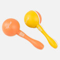 Two Tiger Tribe Maracas, made from sustainable bioplastic, come in vibrant orange and yellow with white accents and the "TIGER TRIBE" brand name printed on each. The handles boast three white stripes near the spherical tops. Arranged diagonally with handles pointing downward, they offer a musical adventure waiting to unfold.