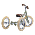 The TryBike - Vintage Green by TryBike is a 2-in-1 tricycle balance bike designed for learning to ride. It features large cream-colored tires, a green frame with the "TryBike" logo, and a brown seat and handlebars. This sturdy tricycle is photographed on a white background.