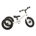 The TryBike - White by TryBike is a versatile 2-in-1 balance bike that can be transformed into a tricycle by adding an extra wheel at the back. It features black handlebars and tires, a small black seat, and proudly displays the word "TRYBIKE" on its frame.