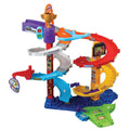 The Vtech Toot Toot Drivers Twist & Race Tower by Vtech is a colorful toy race track set featuring multiple spiraling ramps in blue, gray, red, yellow, and green. It includes a starting gate with a traffic light, a slide, decorative stickers, and a SmartPoint race car. The base is blue with pathways and has a small car attached to the side.