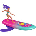 Introducing the Wahu Surfer Dude - Margaret River Maddy: a colorful, self-surfing toy featuring a purple figure with flowing hair riding a surfboard. The surfboard boasts a stunning pink-to-teal gradient with a vibrant flower design. The surfer strikes an iconic pose atop waves illustrated beneath the board.