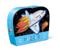 A curved box with a vibrant illustration of a white rocket ship blasting off into space, leaving trails of flames and stars behind. The box reads "PUZZLE" and indicates it's for toddlers ages 2 and up, containing 12 mini jigsaw puzzle pieces to aid hand-eye coordination. The brand name "Crocodile Creek" is at the bottom.