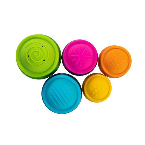 Five vibrant tactile sensory toys, known as the Fat Brain Toys Dimpl Stack by Fat Brain Toys, arranged in a group. Each toy is a different color and features a unique texture pattern: green with swirls, pink with starburst lines, orange with concentric circles, blue with ridges, and yellow with small bumps. This Dimpl Stack provides endless tactile fascination for little hands.