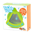 A product image of a green "Fat Brain Toys Tobble Tones" rocking chime toy designed for tummy time, promoting sensory learning and suitable for infants aged 6 months and older. The packaging features musical notes and the brand "Fat Brain Toys" in the bottom right corner.