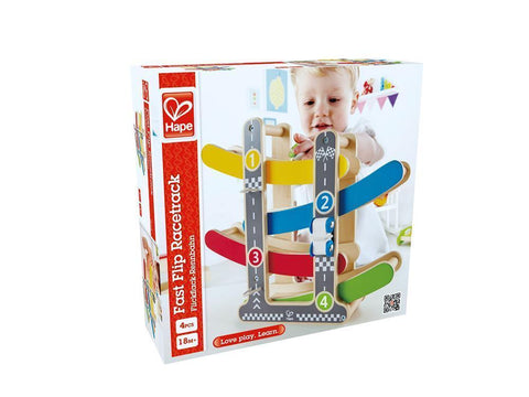 The image shows the Hape Fast Flip Racetrack by Hape in its packaging. Made from wooden materials, it features a colorful multi-level racetrack with numbered tracks and racing cars. The box depicts a smiling child demonstrating how to use the toy.