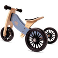 The Kinderboard Tiny Tot Plus in Slate Blue is a small, wooden balance bike designed for toddlers and young children. The bike features a slate blue frame with black handles and seat. Its adjustable seat height ensures comfort as your child grows, while three large, black rubber wheels provide stability and easy maneuverability.