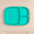 A turquoise Re-Play Divided Tray by REPLAY made from recycled materials rests on a light wooden surface. This eco-friendly tray is rectangular, featuring two smaller compartments on the right and a larger one on the left.